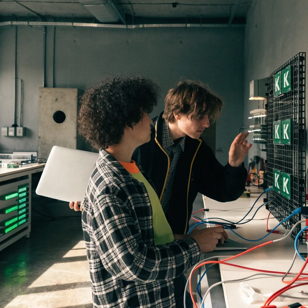 Two learners working at a row of lab workstations during a hands-on DevOps session